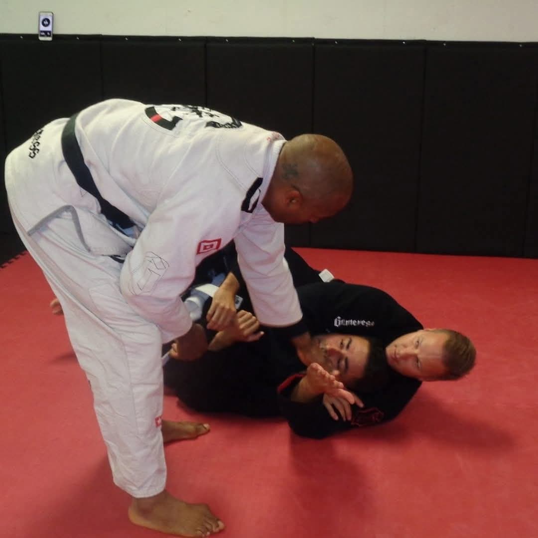 Professor Gideon Ray demonstrating a grip-control technique on two students during a Brazilian Jiu Jitsu class.