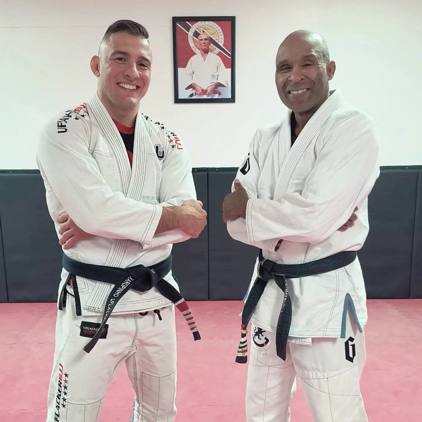 Gideon Ray and his professor Christian Uflacker standing side by side in white gis on the academy mats.